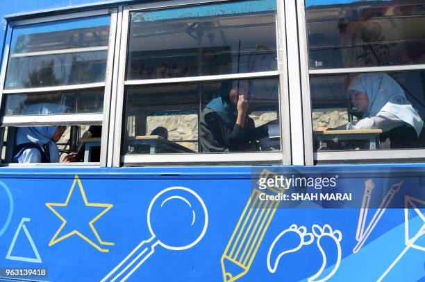 In this photograph taken on April 4 an Afghan girl looks out of a window as others read books in a mobile library bus in Kabul. - The door of the...