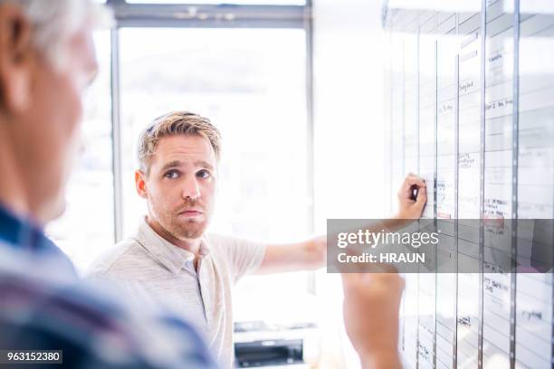 young businessman looking at mature colleague - 40 days stock pictures, royalty-free photos & images