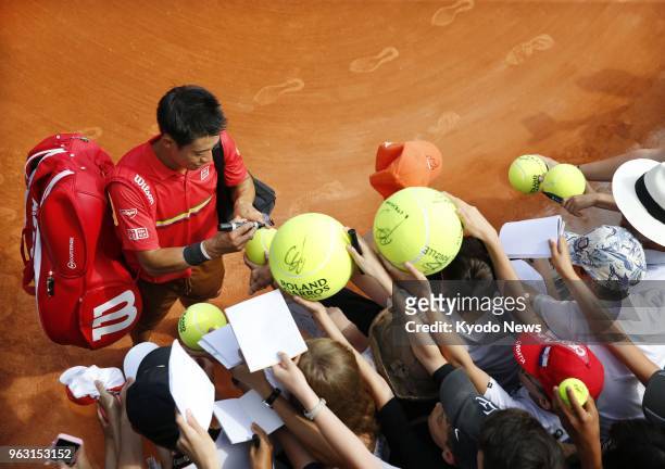 Kei Nishikori of Japan signs autographs for fans after winning 7-6, 6-4, 6-3 against Maxime Janvier of France in the first round of the French Open...
