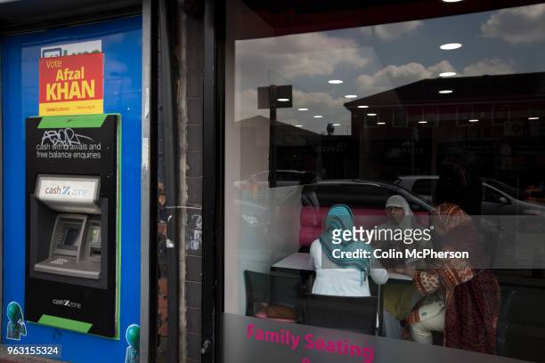 Group of women sitting in a cafe with a General Election poster visible in the Rusholme area of Manchester. A minute's silence was held in memory of...
