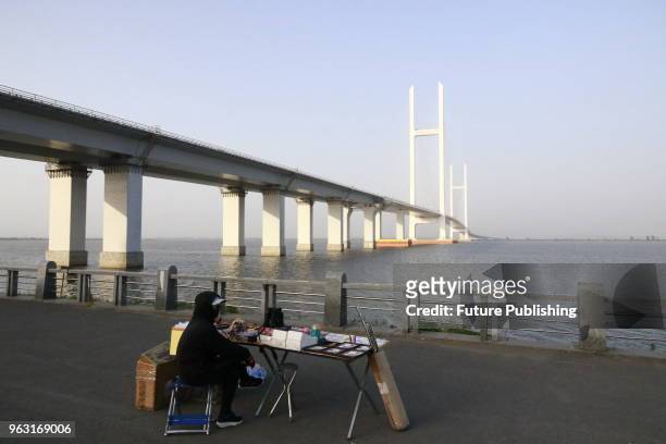 Chinese vendor waits for customers on the river bank near the China-North Korea Yalujiang Bridge across the border river in Dandong in northeast...