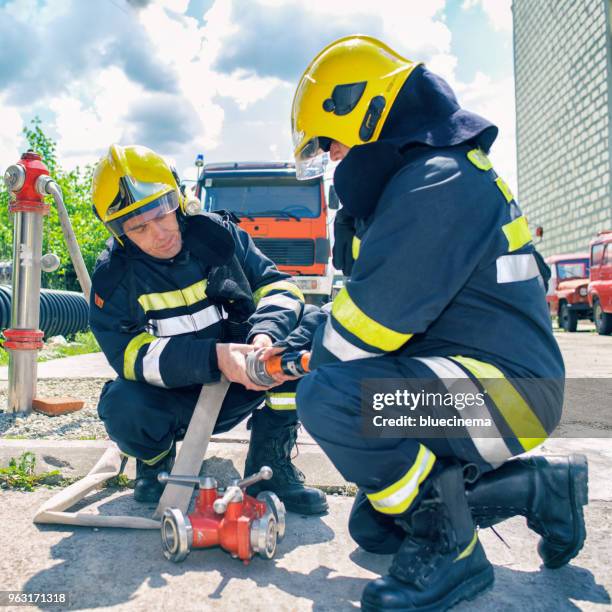 firemans in action connected a fire hose - phosphorescence stock pictures, royalty-free photos & images