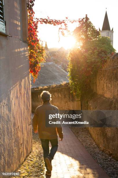 man walks along medieval path in sunlight - finale ligure stock pictures, royalty-free photos & images