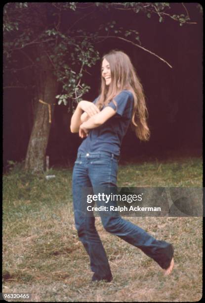 Long-haired, barefoot laughing young woman at the Woodstock music festival, August 1969.