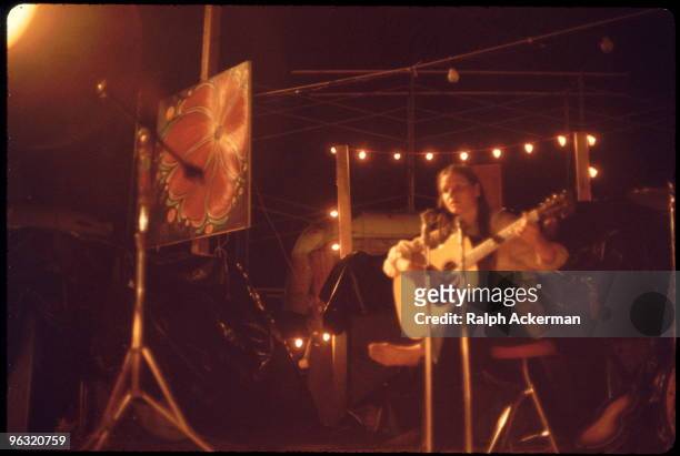 Young woman performer playing guitar on the Hog Farmers' Free Stage, at the Woodstock music festival, August 1969.