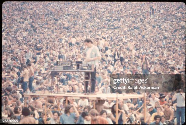 Sound guy stands on scaffolding with his equipment in front of the crowd at the Woodstock music festival, August 1969.