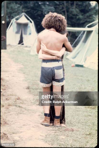 One of the dancers hugs someone on the dirt road as they stand near the tents, at the Woodstock music festival, August 1969.