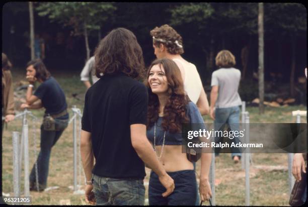 What a smile--two kids in blue--torn jeans, old leather camera bag, blue midriff t-shirt, long hair, amazing smile, at the Woodstock music festival,...