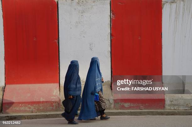 In this photograph taken on May 27, 2018 Afghan clad burqa women walk past blast walls along the roadside in Mazar-i-Sharif.