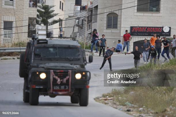 Palestinians throw rocks in response to Israeli soldiers' invasion at Al-Amari Refugee Camp in Ramallah, West Bank on May 28, 2018. According to...