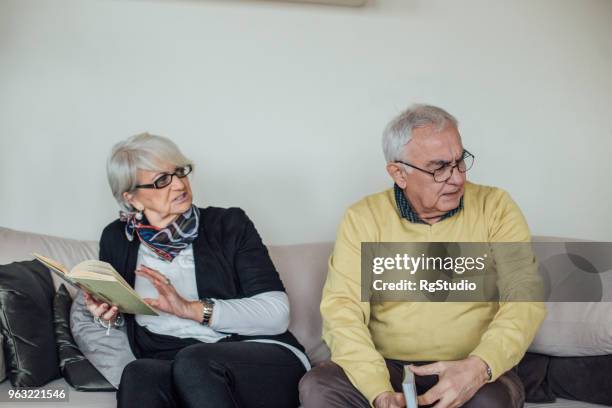 wütend älteres paar am sofa sitzen - grumpy old man stock-fotos und bilder