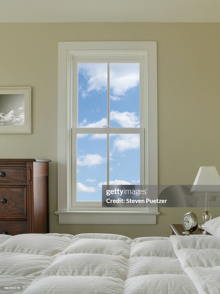 View out bedroom window with blue sky and clouds