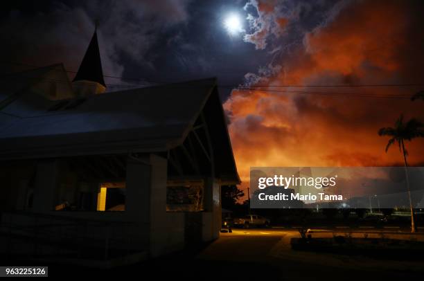 Sacred Heart Church Pahoa stands as lava from a Kilauea volcano fissure illuminates the night sky and volcanic gases rising , on Hawaii's Big Island,...