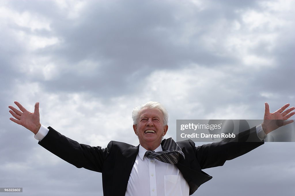 Senior businessman with arms outstretched, smiling