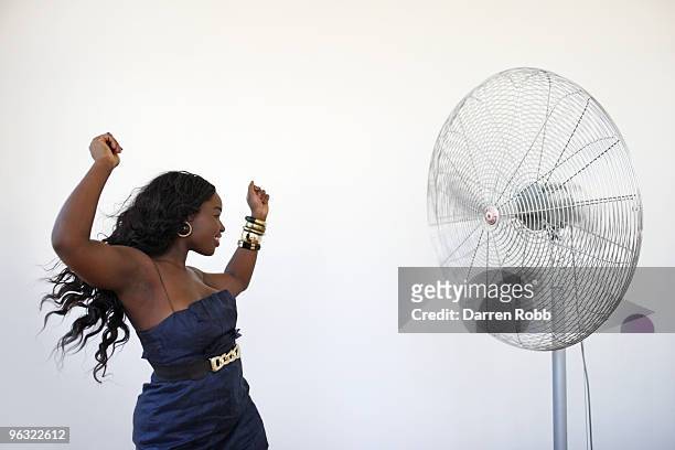 young woman dancing by giant cooling fan - trägerloses kleid stock-fotos und bilder