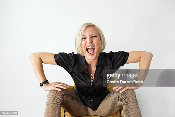 young woman sitting on a chair, shouting - breitbeinig stock-fotos und bilder