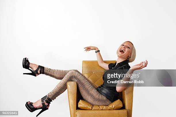young woman sitting on a chair, laughing - armchair white background stock-fotos und bilder