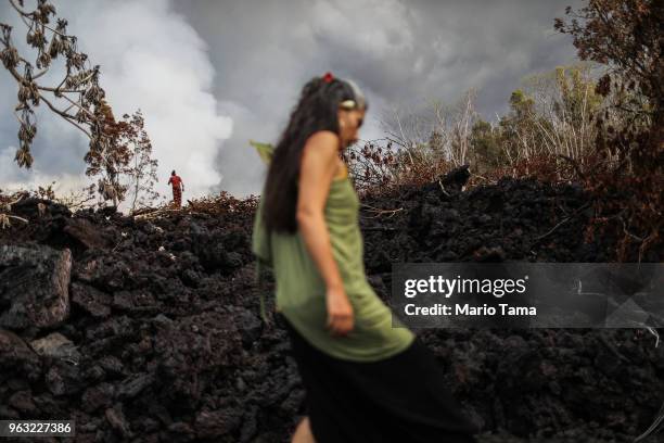 Traditional hula practitioner carries an offering while walking on a cooled recent lava flow from a Kilauea volcano fissure, on Hawaii's Big Island,...