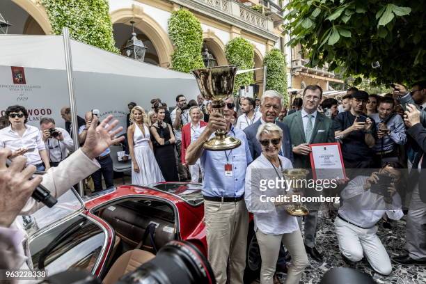 Entrant Albert Spiess, center, holds up the trophy after his 1968 Alfa Romeo Automobiles SpA 33/2 Stradale automobile took the Coppa d'oro Villa...