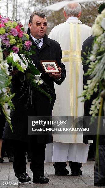 Mourner holds a wreath of flowers and a portrait during the funeral ceremony of Charlotte Francois and Pierre Guilliams, victims of last Wednesday's...