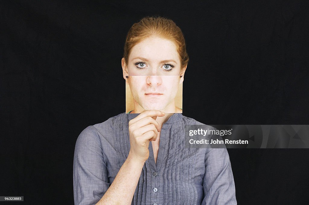 Girl hiding behind paper mask with sad face