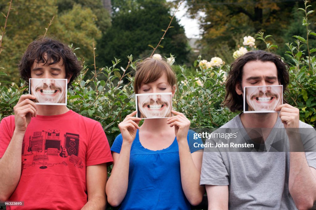 Group hiding behind fake paper masks smiling
