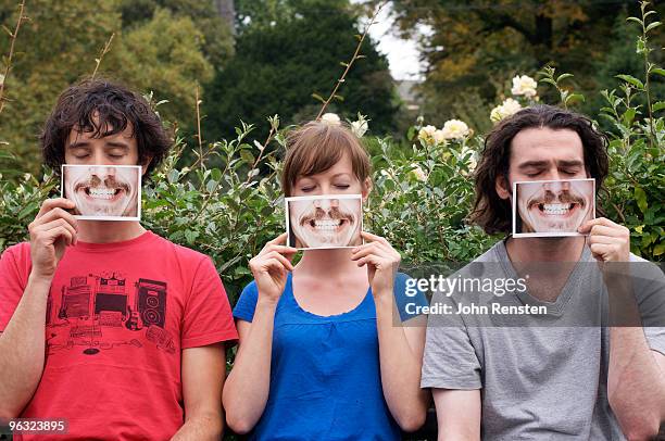 group hiding behind fake paper masks smiling  - fake man stockfoto's en -beelden