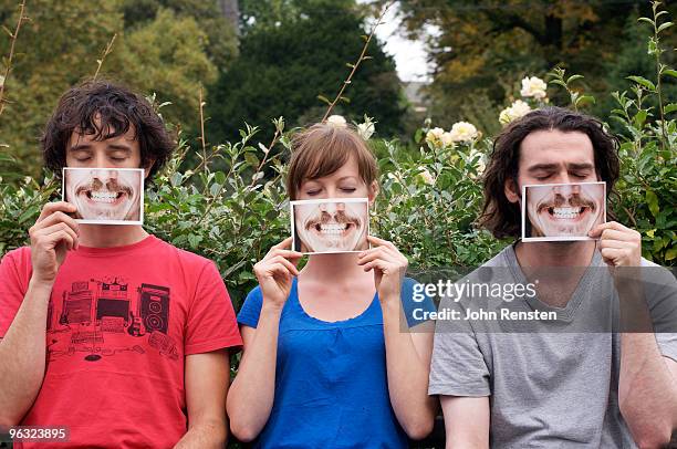 group hiding behind fake paper masks smiling  - fake stock pictures, royalty-free photos & images