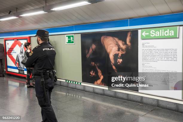 Policeman looks after the painting 'Ixion' by Jose de Ribera displayed on the walls of the Atocha metro station, named since today the Art Station,...