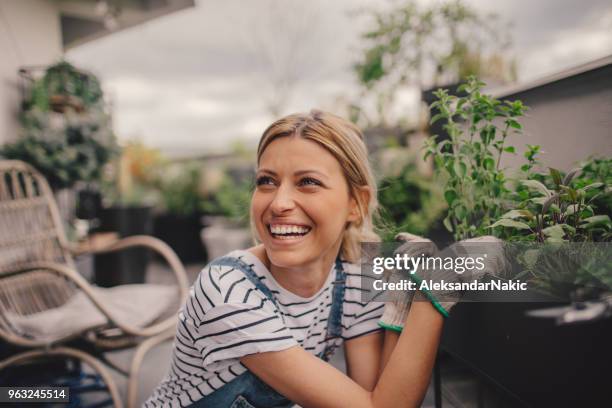 jonge vrouw regelen van de planten in haar tuin op het dak - gardener stockfoto's en -beelden