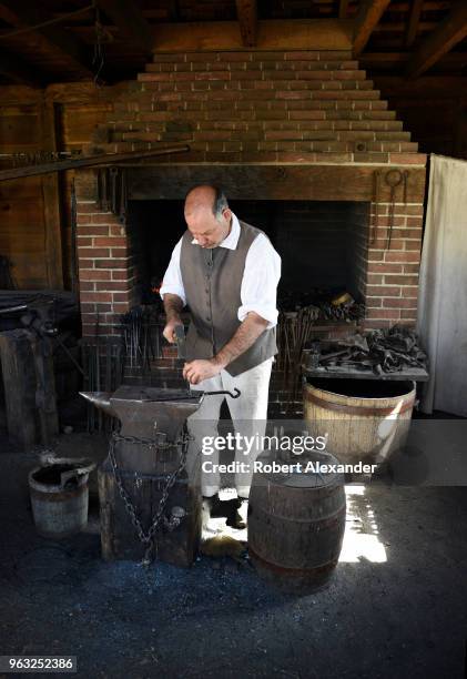 Reenactor in period costume demonstrates how to forge iron objects in the blacksmith shop at Mount Vernon, the plantation owned by George Washington...