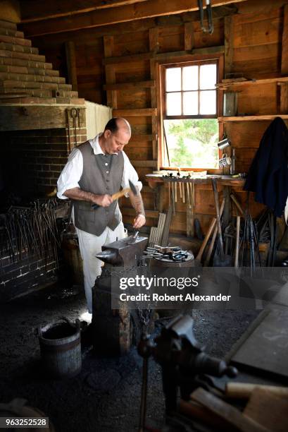 Reenactor in period costume demonstrates how to forge iron objects in the blacksmith shop at Mount Vernon, the plantation owned by George Washington...