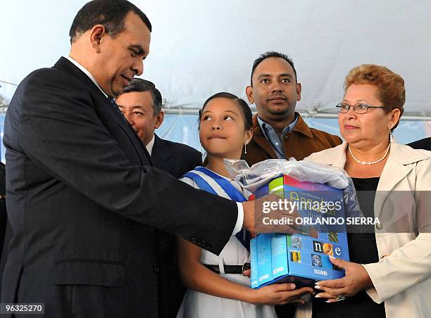 Honduran President, Porfirio Lobo , hands a set of textbooks to both a student and the principal of the Republic of Paraguay Application School,...