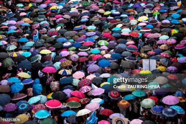 People cover themselves with umbrellas as they take part in a peace march under the rain in Myitkyina, Kachin state, on May 28, 2018.