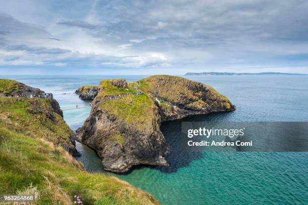 tourists crossing the carrick-a-rede rope bridge, northern ireland - ballycastle stock pictures, royalty-free photos & images