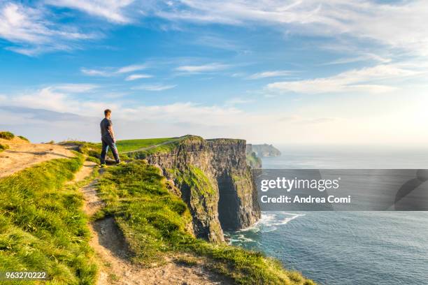 a man standing on the cliffs admires the sunset - klippe stock-fotos und bilder