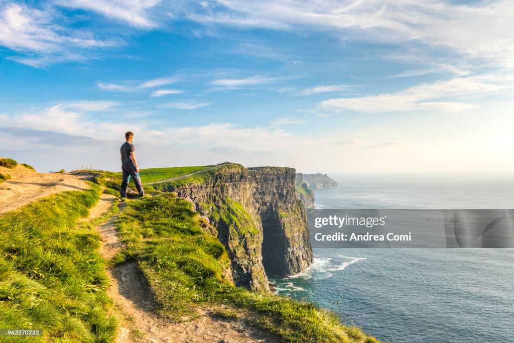 A Man standing on the cliffs admires the sunset