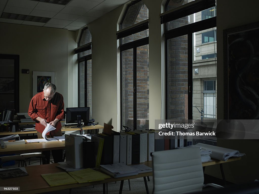 Businessman examining plans in empty office