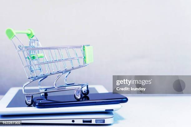 online business and e-commerce or shopping online concept. shopping basket on top of stack of laptop, tablet and mobile phone. wireless technology for business with free copy space. - shopping basket bildbanksfoton och bilder