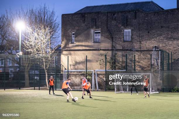 al aire libre urbano iluminado campo con grupo de hombres jugando al fútbol - amateur football fotografías e imágenes de stock