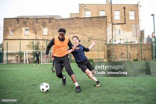 joven a lucha contra oponente en campo de fútbol al aire libre - amateur football fotografías e imágenes de stock