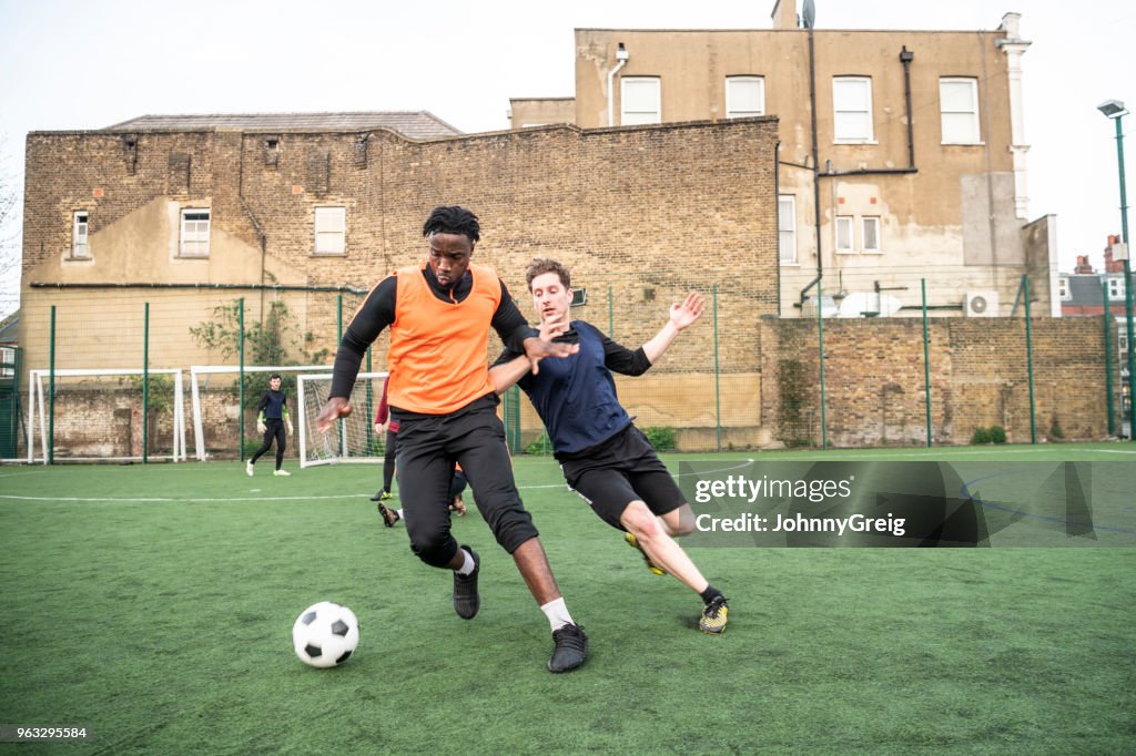 Young man tackling opponent on outdoor football pitch