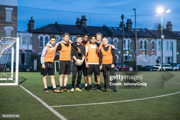 amateur football team portrait at night on urban floodlit pitch - mens soccer team stock pictures, royalty-free photos & images