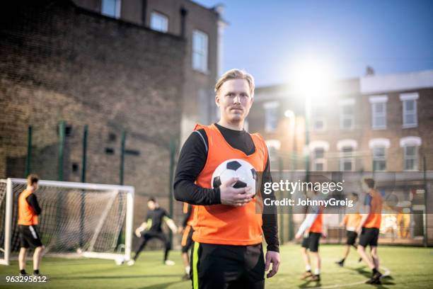 夜のピッチでサッカーを保持している 30 代の自信のフットボール選手の肖像 - アマチュア選手 ストックフォトと画像