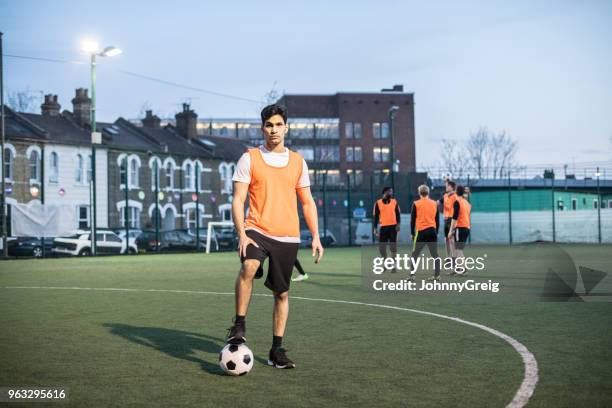 retrato de hombre futbolista en cancha con pie en bola y equipo compañeros en segundo plano - male feet fotografías e imágenes de stock