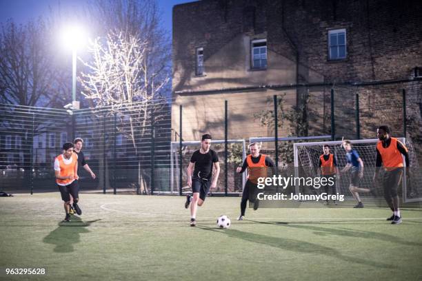 tiro de la acción de los futbolistas en un campo urbano en la noche con dos jugadores para la bola - amateur football fotografías e imágenes de stock