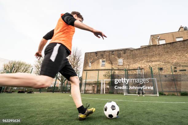 ángulo bajo de hombre futbolista a punto de tomar un tiro en meta - amateur football fotografías e imágenes de stock