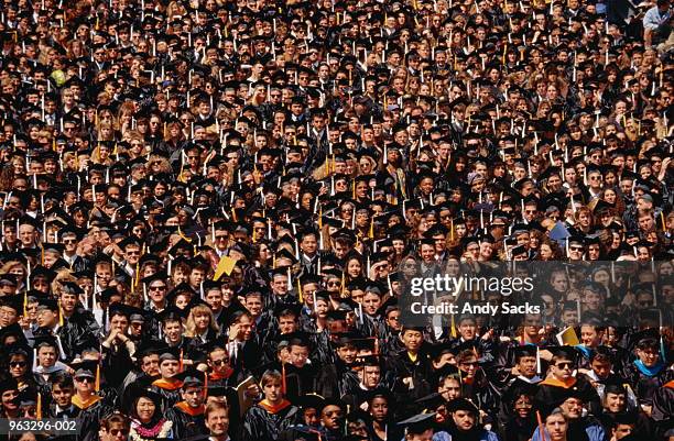 crowd of graduates in cap and gown - graduation crowd stock pictures, royalty-free photos & images