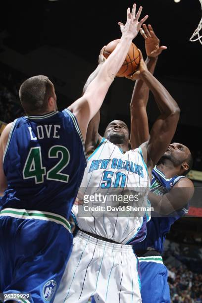 Emeka Okafor of the New Orleans Hornets goes up for a shot against Kevin Love and Al Jefferson of the Minnesota Timberwolves during the game at...