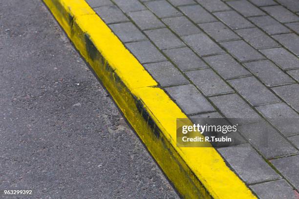 yellow kerb line on the asphalt road - kerb stock-fotos und bilder